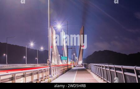 Langzeitbelichtung der Aramchangyo-Brücke, entworfen von SK E&C in der Nähe der Stadt Sejong in Südkorea, mit roten Lichtstreifen von vorbeifahrenden Autos. Enthält Stockfoto