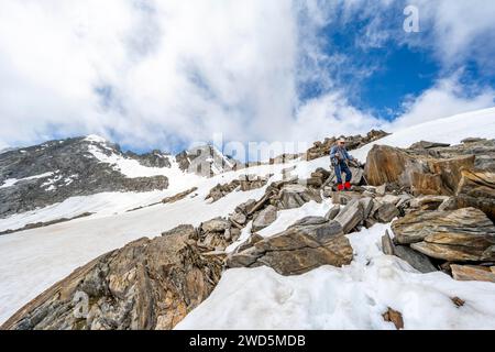 Bergsteiger auf einem Wanderweg zwischen Schnee, Abfahrt vom Gipfel des Schoenbichler Horns, Blick auf die verschneite Berglandschaft mit Gipfel Stockfoto