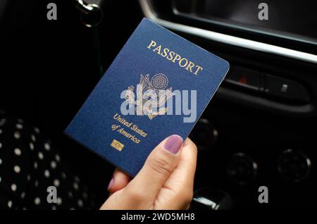 Nahaufnahme einer nicht identifizierten Hand, die einen geschlossenen amerikanischen Pass hält, was Reisepläne vorschlägt. Stockfoto