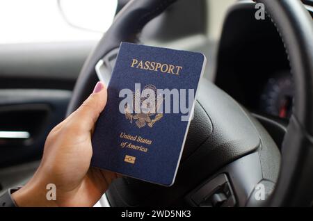 Nahaufnahme einer nicht identifizierten Hand, die einen geschlossenen amerikanischen Pass hält, was Reisepläne vorschlägt. Stockfoto