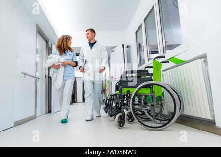 Niedrigwinkelansicht von Arzt und Krankenschwester, die mit Rollstühlen den Krankenhausflur entlang gehen Stockfoto