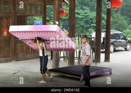 龙胜镇 (龙胜县) 中國 Longsheng, Dazhai Longji Ping'an Zhuang, China; Eine Chinesin trägt eine große Matratze auf ihren Schultern; 一名中國婦女肩上扛著一張大床墊 Stockfoto