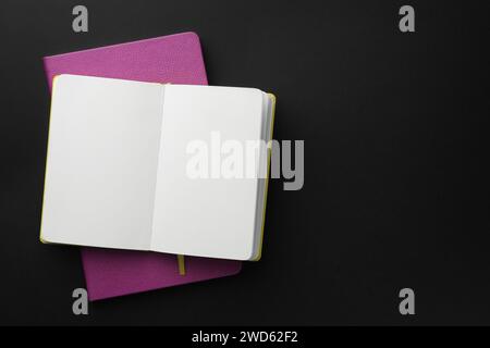 Notizbücher auf schwarzem Hintergrund, Draufsicht. Leerzeichen für Text Stockfoto