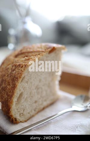 Das Leben ist besser mit Brot – Nahaufnahme von frisch geschnittenem Brot mit Krümeln auf einer Leinenserviette neben einem kleinen Kaffeelöffel. Stockfoto