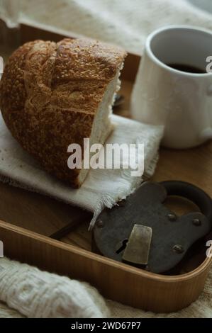 Rustikaler Charme - knuspriges Sauerteigbrot steht neben einer Tasse Kaffee auf einem hölzernen Frühstückstablett. Stockfoto