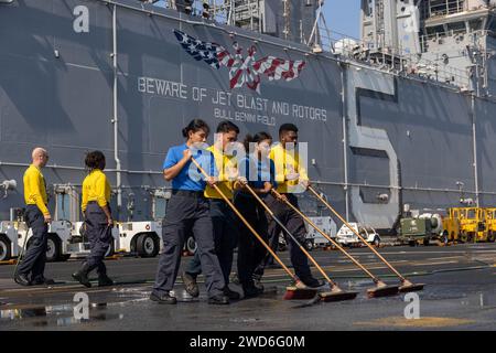 Auf See. Dezember 2023. Sailors schrubbt das Flugdeck an Bord des amphibischen Angriffsschiffs USS Bataan (LHD 5) der Wasp-Klasse, 17. Dezember. Komponenten der Bataan Amphibious Ready Group und der 26th Marine Expeditionary Unit (Special Operations Capable) werden im Einsatzgebiet der 5th Fleet der USA eingesetzt, um die Sicherheit und Stabilität im Nahen Osten im Seeverkehr zu gewährleisten. (Kreditbild: © U.S. Navy/ZUMA Press Wire) NUR REDAKTIONELLE VERWENDUNG! Nicht für kommerzielle ZWECKE! Stockfoto