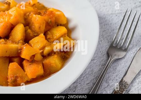 Hackfleisch und Kartoffelschale auf weißem Porzellanteller auf Steintisch Stockfoto