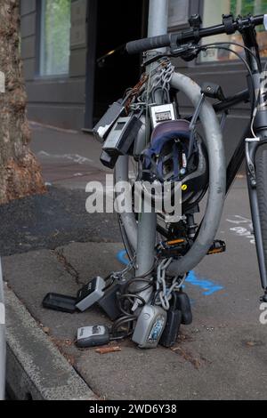 Eine unansehnliche Sammlung von Kombinationsschlüsselkästen für Kurzzeitwohnungen im Airbnb-Stil, die wie eine Punk Rock Halskette an einen Versorgungsmast gekettet werden können Stockfoto