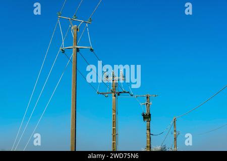 Die Stromleitungen gegen einen klaren blauen Himmel in einer ländlichen Landschaft Stockfoto