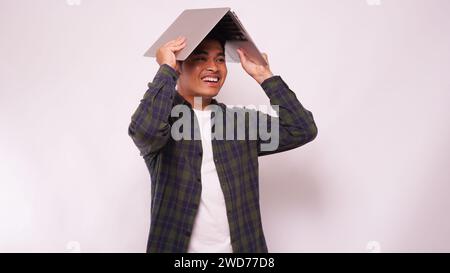 Asiatischer Mann mit einem Laptop auf dem Kopf auf weißem Hintergrund Stockfoto