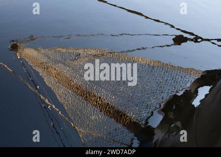 Schiffsbug mit Auslegerausleger und eng geknotetem Auslegernetz vor dem Vormast eines Segelschiffes, das im plätschernden Wasser gespiegelt wird. Hintergrundbild Stockfoto