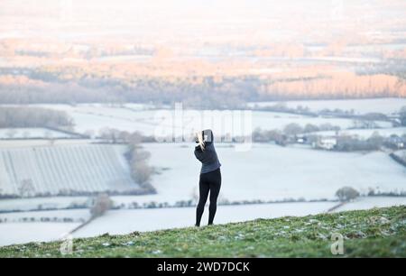 Brighton UK 19 Januar 2024 - Ein Läufer hält an um die Aussicht am Devils Dyke entlang des South Downs Way nördlich von Brighton an einem weiteren frostigen Morgen zu genießen aber mildes Wetter wird für die nächsten Tage in Großbritannien prognostiziert : Credit Simon Dack / Alamy Live News Stockfoto