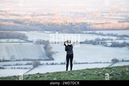 Brighton UK 19 Januar 2024 - Ein Läufer hält an um die Aussicht am Devils Dyke entlang des South Downs Way nördlich von Brighton an einem weiteren frostigen Morgen zu genießen aber mildes Wetter wird für die nächsten Tage in Großbritannien prognostiziert : Credit Simon Dack / Alamy Live News Stockfoto