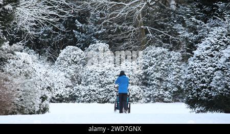 Ein Mann geht mit einem Kinderwagen auf einem mit Schnee bedeckten Weg im Stadtpark Hamburg entlang. Winterhude Hamburg *** Ein Mann läuft mit einem Kinderwagen auf einem schneebedeckten Weg im Hamburger Stadtpark Winterhude Hamburg Stockfoto