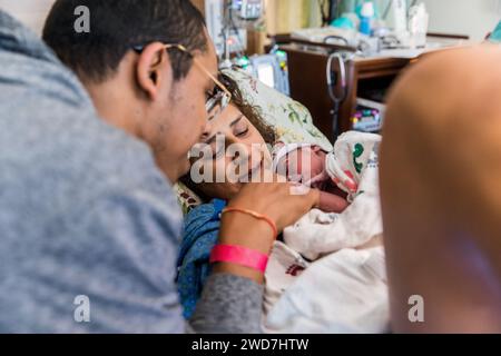 Multirassisches Paar lächelt Neugeborenes nach Krankenhausgeburt an Stockfoto