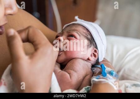 Multirassisches neugeborenes Baby saugt nach der Geburt an Mamas Finger Stockfoto