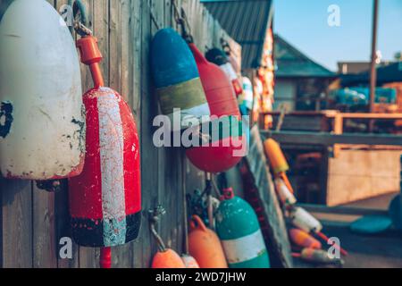 An einem späten Nachmittag hängen bunte Bojen an einem Holzzaun. Stockfoto