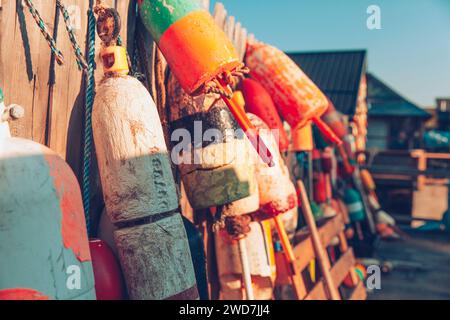 An einem späten Nachmittag hängen bunte Bojen an einem Holzzaun. Stockfoto