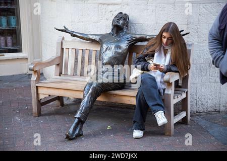 Weibliche Besucherin der Carnaby Street „in Conversation“ mit John Lennon Statue „Imagine“ von Bildhauer Lawrence Holofcener. London. UK. (137) Stockfoto