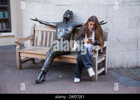 Weibliche Besucherin der Carnaby Street „in Conversation“ mit John Lennon Statue „Imagine“ von Bildhauer Lawrence Holofcener. London. UK. (137) Stockfoto