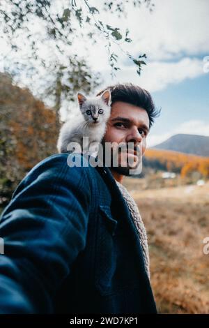 Winziges Kätzchen, das in der Natur auf der Schulter des Mannes sitzt Stockfoto