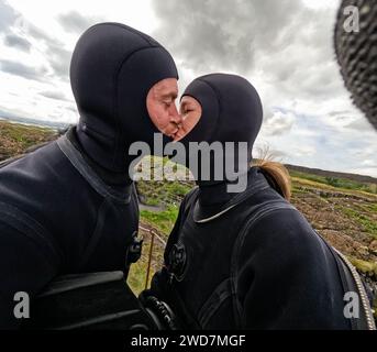 Ein paar Küsse in Nassanzügen, bevor man ins Wasser zum Schnorcheln geht Stockfoto