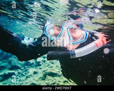 Frau schnorchelt in klarem Gletscherwasser und Neoprenanzug Stockfoto