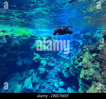Die Person im Trockenanzug macht Unterwasserfotos im klaren Gletscherschlucht Stockfoto