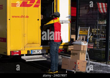 Lieferdienst in Aktion: DHL-Zusteller bereitet Paketlieferung bei REWE vor. , Deutschland, Rheinland-Pfalz, Speyer, 19.01.2024, auf dem Foto ist ein DHL-Zusteller zu sehen, der neben einem offenen, gelben Lieferwagen steht und Pakete auf einem Transportwagen vor sich hat. Im Hintergrund ist ein REWE-Schild erkennbar, was darauf hinweist, dass die Lieferung in der Nähe eines REWE-Supermarktes stattfindet. *** Zustelldienst in Aktion DHL-Zustellfahrer bereitet Paketzustellung bei REWE, Deutschland, Rheinland-Pfalz, Speyer, 19 01 2024 vor, das Foto zeigt einen DHL-Zustellfahrer, der neben einem steht Stockfoto