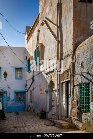 Alte weiße, blaue und gelbe Häuser in einem Innenhof in der Medina von Kairouan, Tunesien. Kairouan ist die 4. Heiligste Stadt im Islam und gehört zum UNESCO-Weltkulturerbe Stockfoto