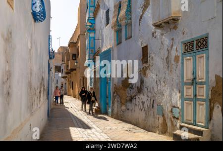 Tunesier laufen an Häusern in der alten Medina von Kairouan in Tunesien vorbei. Kairouan ist die 4. Heiligste Stadt im Islam und gehört zum UNESCO-Weltheritag Stockfoto