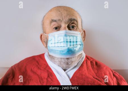 Ein älterer Mann trägt eine Gesichtsmaske und einen Weihnachtsmann-Anzug Stockfoto