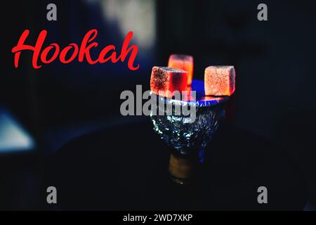 Heiße rote Kohlen auf Folie auf einer Shisha-Schüssel, Nahaufnahme auf schwarzem Hintergrund Stockfoto