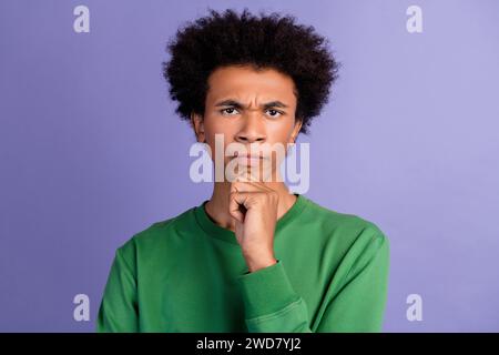 Foto von ernsten selbstbewussten Mann gekleideten grünen Pullover, der Sie Arm Kinn isoliert violett Hintergrund sieht Stockfoto