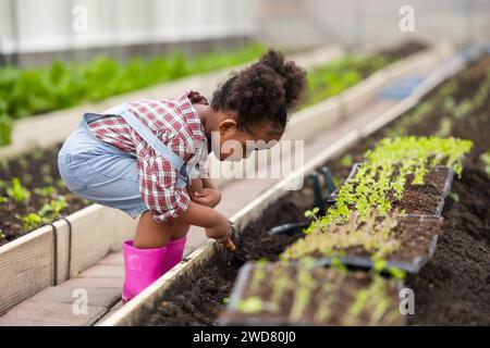 Afrikanisches schwarzes Kind beim Pflanzen des grünen Baumes in der Landwirtschaft. Kinder lieben das Naturkonzept. Stockfoto