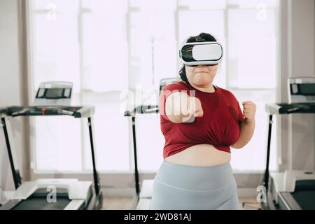 Fette Frauen mit VR-Headset spielen visuelles Reality-Sportspiel für Sport. Menschen, die moderne Technik für das Heilbehandlungskonzept nutzen. Stockfoto