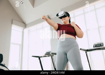 Fette Frauen mit VR-Headset spielen visuelles Reality-Sportspiel für Sport. Menschen, die moderne Technik für das Heilbehandlungskonzept nutzen. Stockfoto