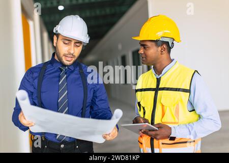 Das Team der Ingenieure, das mit der Arbeit des Architekten arbeitet, inspiziert das Bauprojekt der großen Gebäudefabrik mit Grundriss Stockfoto