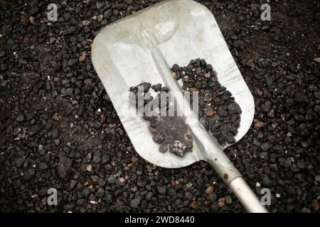 Die Schaufel liegt auf dem Kies. Stahlschaufel. Kleiner zerkleinerter Stein. Werkzeug für den Bau. Stockfoto