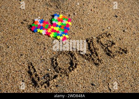 Puzzle Liebe am Ufer: Lebendiges Herz entsteht aus sandiger Hingabe, einer farbenfrohen Valentinstag-Symphonie. Stockfoto