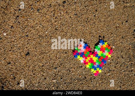 Puzzle Heart: Liebe und Verbindung dargestellt durch bunte Puzzleteile am Strand, die eine einzigartige und besondere Bindung symbolisieren. Stockfoto