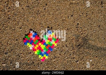 Puzzle Heart: Liebe und Verbindung dargestellt durch bunte Puzzleteile am Strand, die eine einzigartige und besondere Bindung symbolisieren Stockfoto