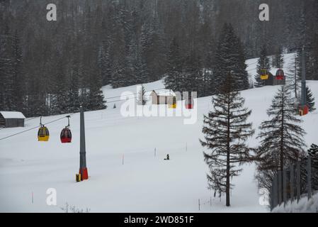 Farbenfrohe Seilbahn im Winter über verschneiten Wald Stockfoto
