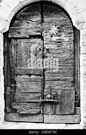 Alte Holztür eines Hauses in der Stadt Besalú, Girona, Spanien. Schwarzweiß-Effekt Stockfoto