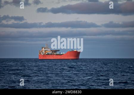 Bild eines Schiffes im blauen Meer an einem sonnigen Tag mit bewölktem grauem und blauem Himmel. Stockfoto