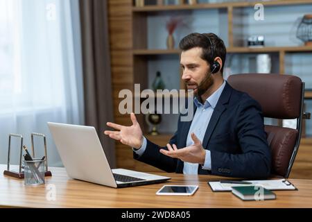 Reifer Geschäftsmann mit Headset, der an einer Online-Telefonkonferenz teilnimmt, während er von einem Home Office aus aus arbeitet. Stockfoto