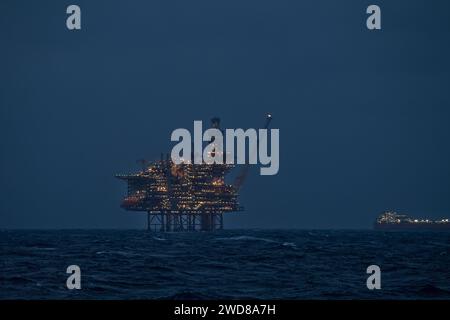 Nahaufnahme des beleuchteten Bohrgeräts und des schwimmenden Lagertankers für die Produktion bei Nacht im Ozean. Stockfoto