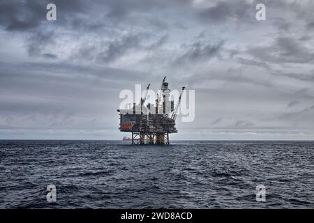 Panoramablick auf Offshore-Öl und Gasöl, das an einem grau bewölkten Tag im Meer abgeflossen ist, mit einem Bohrgerät am Horizont. Stockfoto
