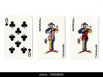 Alte Spielkarten, die ein Paar Joker und eine schwarze acht auf weißem Hintergrund zeigen. Stockfoto