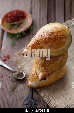 Köstliche Samsa mit Lammfleisch und Gewürzen, die in Tandoor auf hölzernem Hintergrund gekocht werden. Usbekische und zentralasiatische Küche Konzept Stockfoto